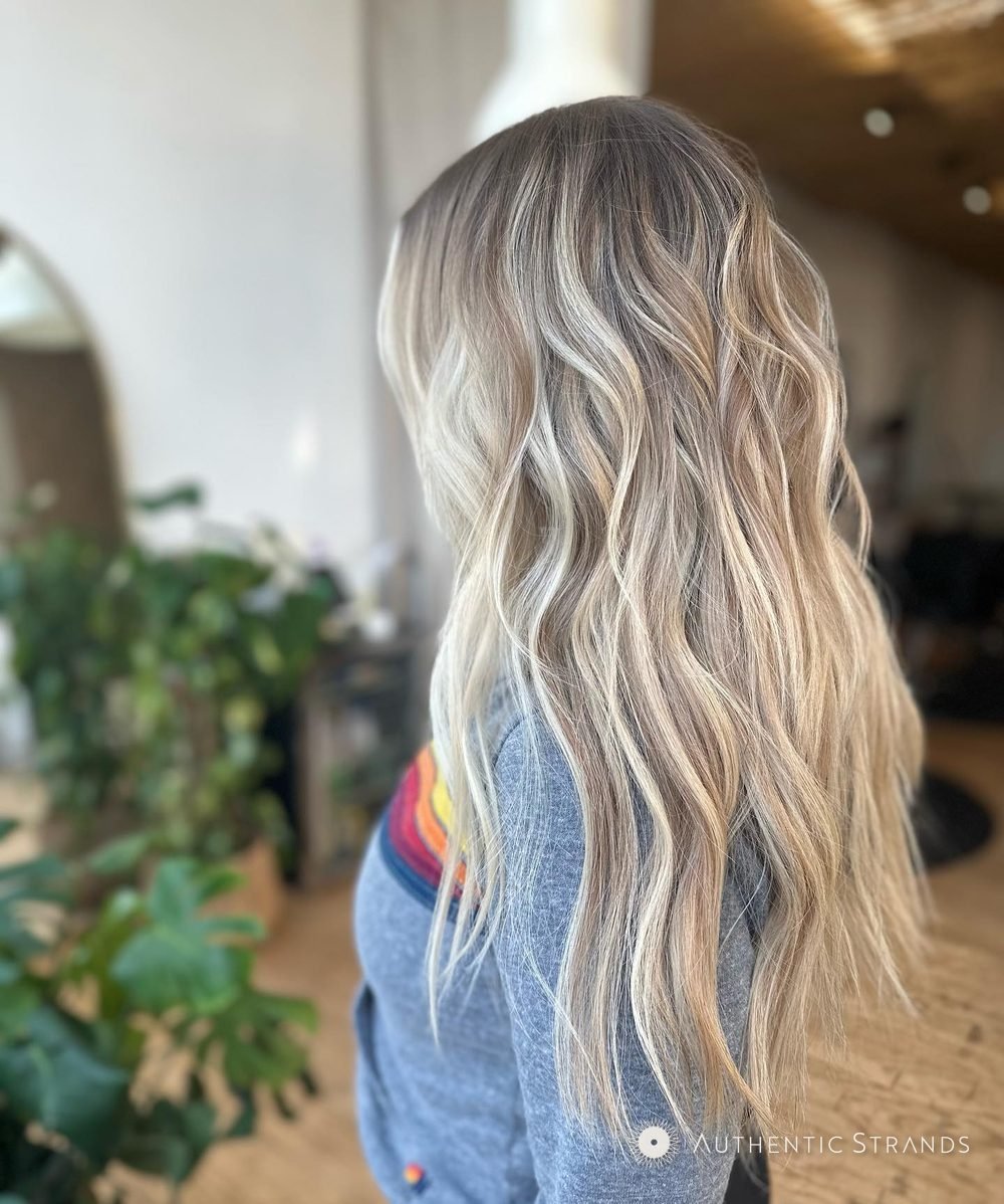 Back view of long rooted blonde balayage waves in the studio
