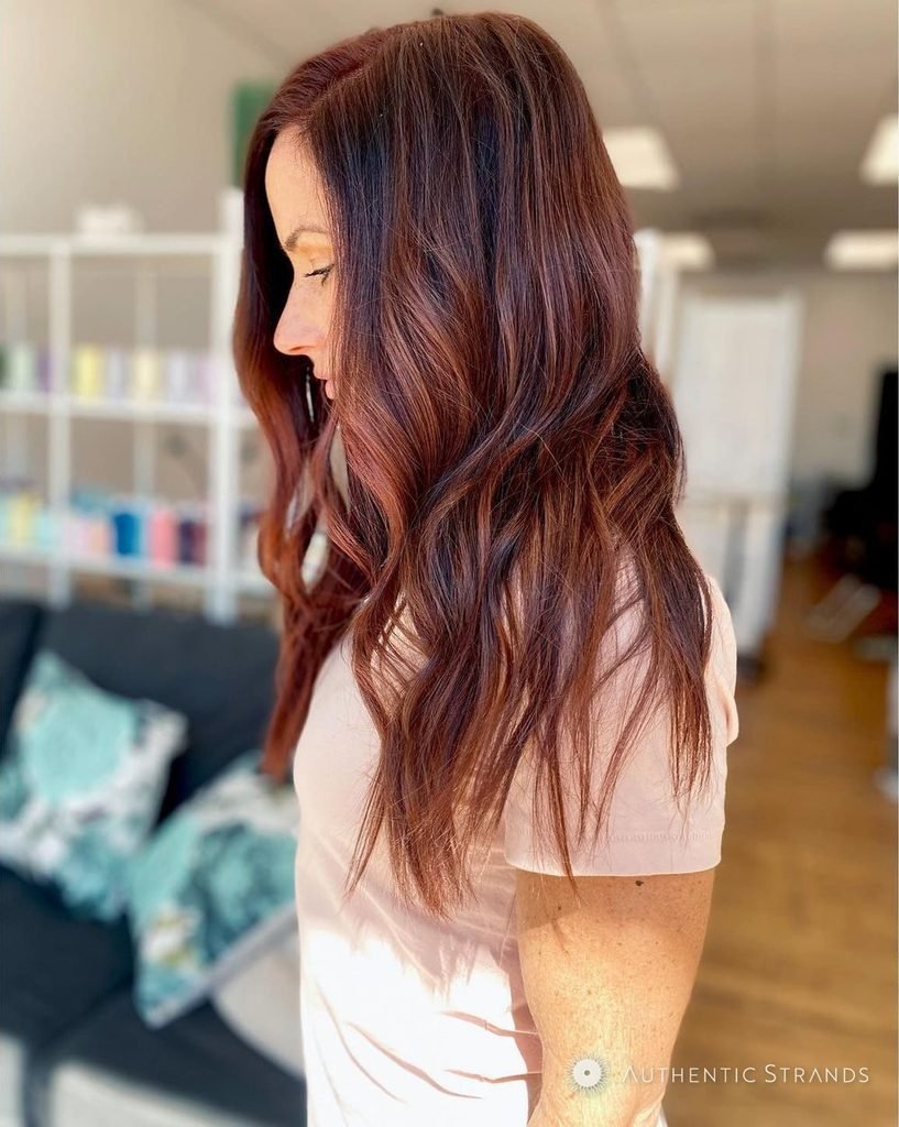 Side profile of long wavy copper-auburn hair in a Columbus salon