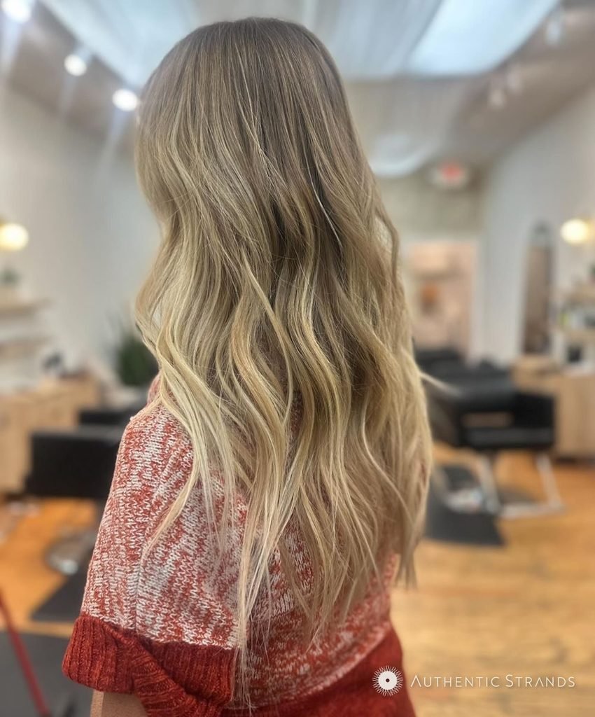 Back view of long wavy honey blonde hair with a lived-in root